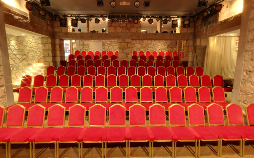 Les fauteuils rouges et les murs de pierre du Théâtre des Muses